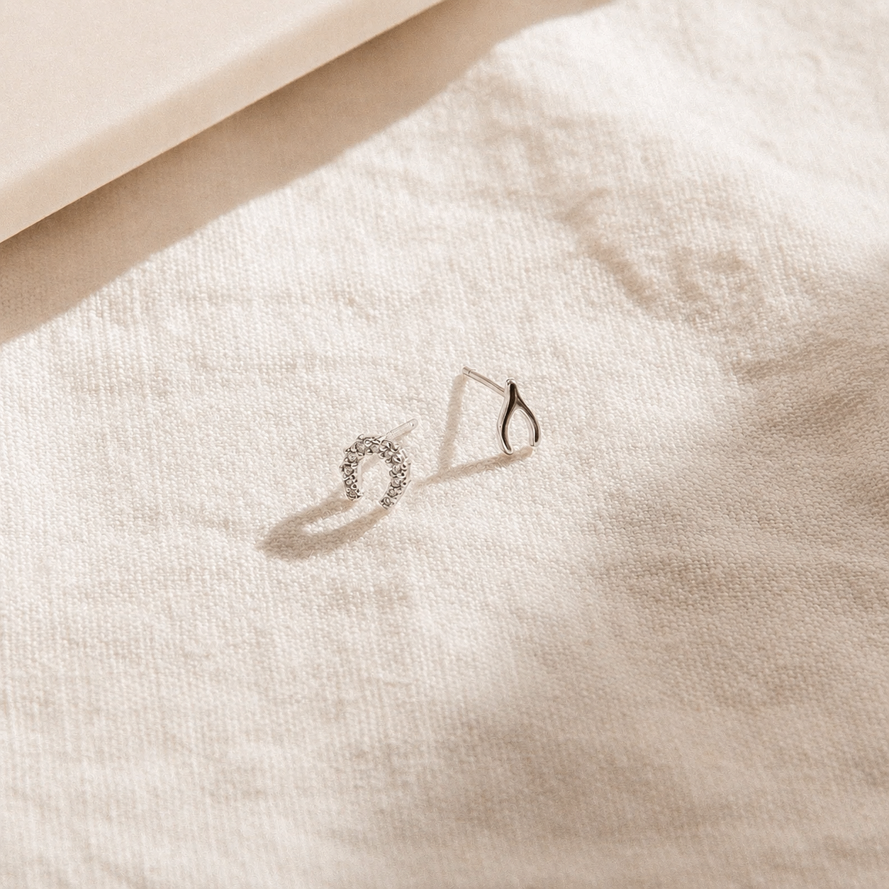 Silver earring on a textured beige surface