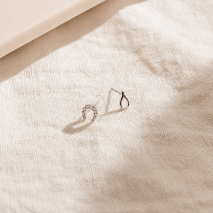 Silver earring on a textured beige surface
