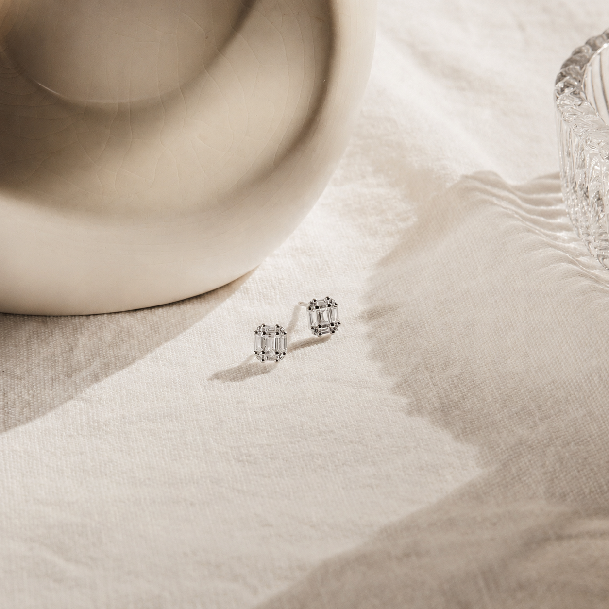 Pair of silver earrings on a textured beige surface