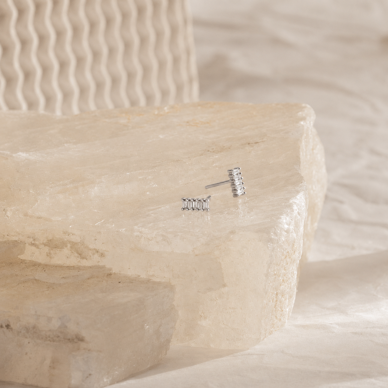 Silver earrings on a stone surface with a soft background