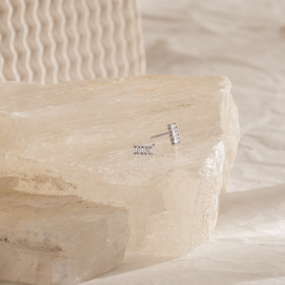 Silver earrings on a stone surface with a soft background