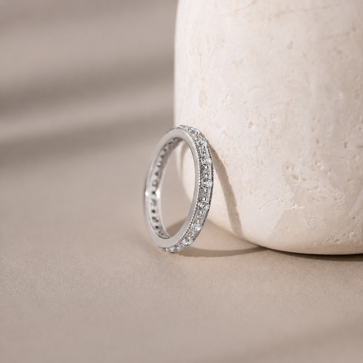 Silver ring with small diamonds on a beige stone surface